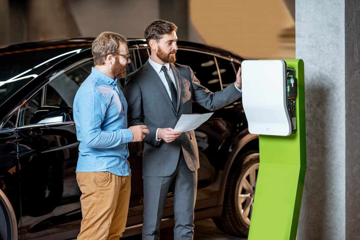 client avec un vendeur au showroom devant borne electrique